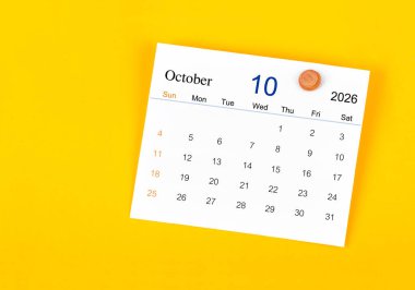 Ekim 2026 Kart takvimi ve sarı duvarda tahta raptiye.