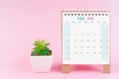 Mayıs 2026 için masa takvimi pembe arka planda bitki örtüsü ile.