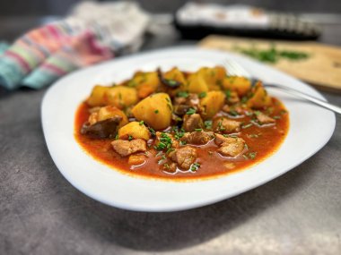 Beyaz tabakta patatesli hindi yahnisi. Mutfaktan çekilen detaylar.