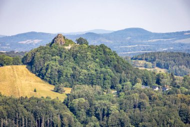 Distant view of rocky ruins of Tolstejn Castle in summer wooded landscape. Lusatian Mountains, Czech Republic, Europe. clipart