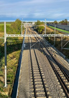 Açık bir günde, yeşil kablolar ile çevrili ve elektrik yüklü demiryolu hatlarının havadan görüntüsü seyahat ve bağlantı hissi veriyor..