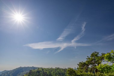 Parlak güneş ışığıyla aydınlatılan eşsiz bulut oluşumlarıyla dolu çarpıcı bir gökyüzü, doğal hava fenomeninin güzelliğini ve mucizesini gösteren sanatsal bir sahne yaratıyor..