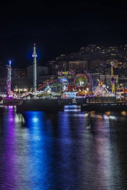 The carnival lights beautifully reflect on the calm water, creating a truly magical atmosphere at night clipart