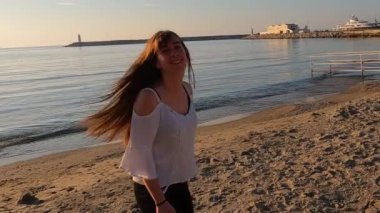 Genç kız sahilde yürüyor ve eğleniyor.