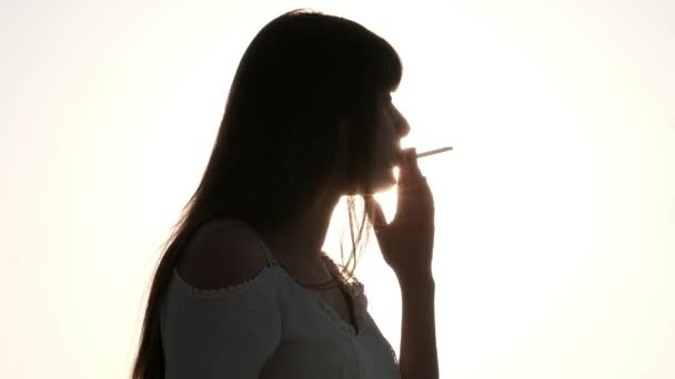 Молодая Девушка Курит Сигарету Перед Солнечными Лучами — стоковое видео
