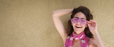 Pembe parti gözlükleriyle gülümseyen genç ve güzel kadın.