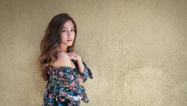 Güzel genç bir kadın grunge duvarının önünde poz veriyor.