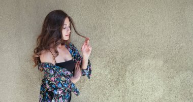 Güzel genç bir kadın grunge duvarının önünde poz veriyor.