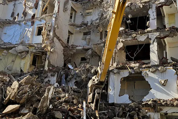 Binanın yıkımı. Kazıcı eski evi yıkıyor. Uzun silahlı yıkım makinesi bir binayı yıkarken görüldü.