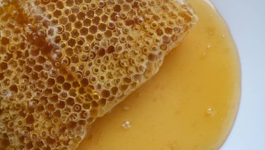 Bal, bal peteğinin üzerinden akıyor.