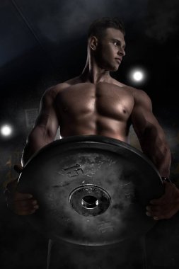 Çekici, uzun boylu, kaslı vücut geliştirici orta yaş fitness merkezinde ağır kaldırımlar yapıyor. Yaratıcı fotoğraf, dış hatlar, kaslar öne çıkıyor. Güzel vücut, fizik, rahatlama, seksi erkek, genç vücut geliştirme kavramı.