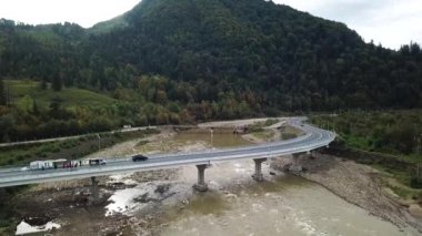Aerial view of a road bridge under construction. road and bridge under construction. view from the sky. Modernization of the structure across the river. Black long road. Asphalt. Workers on a large