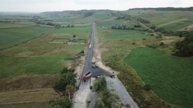 Asfalt kaldırım taşı, paten ve kamyon asfaltlama sırasında yol onarım alanında. Yol yapım ekipmanları. İşçiler tamir ediyor. Otoyolun yakınında kamyonlar çalışıyor. Arabalar yolda ilerliyor. Yeni