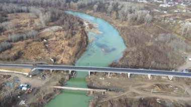 Aerial view of a road bridge under construction. road and bridge under construction. view from the sky. Modernization of the structure across the river. Black long road. Asphalt. Workers on a large