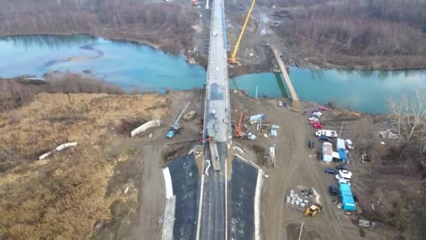 一座正在修建的公路桥的空中视图 正在修建的公路和桥梁 从天而降 河对岸结构的现代化 黑色的长路阿司匹林 大范围的工人 — 图库视频影像