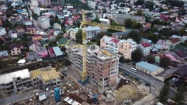 空中飞行飞越一个拥有各种重型机械和建筑工人的新建筑发展基地在该地区工作 下面是一座公寓大楼屋顶的空中俯瞰 — 图库视频影像