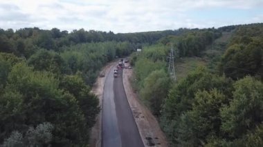 Asfalt kaldırım taşı, paten ve kamyon asfaltlama sırasında yol onarım alanında. Yol yapım ekipmanları. İşçiler tamir ediyor. Otoyolun yakınında kamyonlar çalışıyor. Arabalar yolda ilerliyor. Yeni