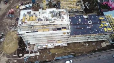 Aerial Flight Over a New Constructions Development Site with Diverse Heavy Machinery and Construction Workers are Working in the Area.Aerial top down view on the rooftop of an apartment building under