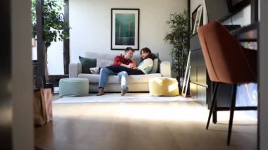 Romantik çift, şık, güneşli bir dairede rahat koltuklarında birlikte vakit geçiriyorlar.