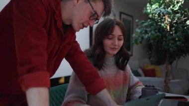 İki tasarımcı bir projeyi tartışıyorlar, gülümsüyorlar ve evlerindeki bir tablette birlikte çalışıyorlar.