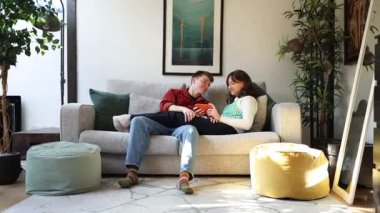 Romantik çift, şık ve modern dairelerinde rahat bir kanepede birlikte vakit geçiriyorlar.