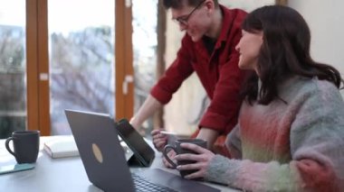 İki genç girişimci, modern ofislerinde kahve molası vererek bir projede işbirliği yapıyorlar.