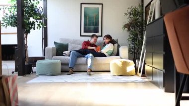 Genç çift kanepelerinde dinleniyor, sosyal medyada gezinirken birlikte güzel vakit geçiriyorlar.