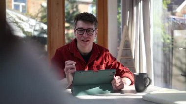 Yaratıcı profesyonel, bir tablet ve stil kullanarak ev ofisinden online bir toplantı düzenliyor.