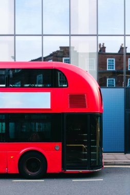 Modern cam binanın yakınına park edilmiş parlak kırmızı Londra otobüsü geleneksel tuğla mimarisini yansıtıyor. Reklam potansiyeli olan kentsel kombinasyonlar sergiliyor.