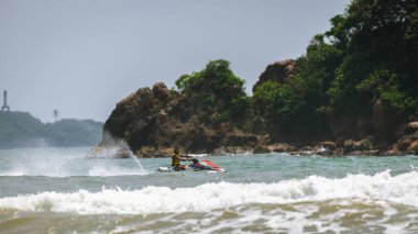Weligama, Sri Lanka - 10 29 2022: Riding a jet ski close to the shore of a small island, a beautiful natural landscape view.