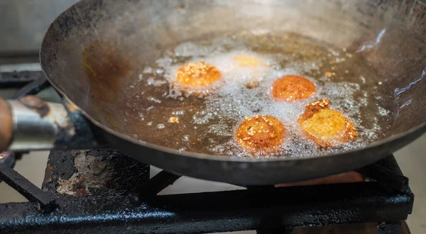 Kızarmış falafel köfteleri tavada, sıcak yemek yağları kaynıyor ve falafel topları altın rengi kahverengiye dönüyor.