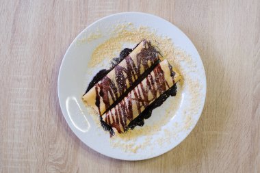 Çikolata soslu tatlı krepler ve üzerine kırıntılar serpiştirilmiş