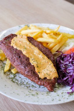 Kızartma ve kırmızı lahana ile servis edilen krema soslu ızgara etli köfte.