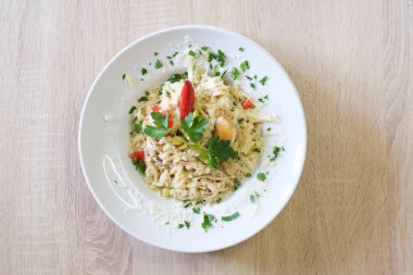 Maydanoz ve peynirle süslenmiş kremalı tavuk ve sebzeli risotto.