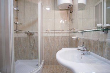 Duş lavabosu ve döşeli duvarları olan küçük bir banyo.