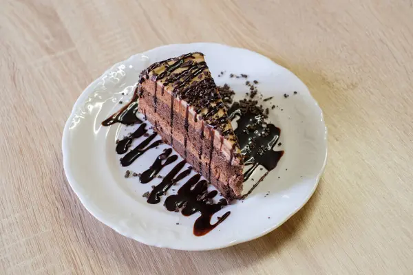 Çikolata sosu ve çikolata parçacıkları serpiştirilmiş çikolata katmanlı pasta.