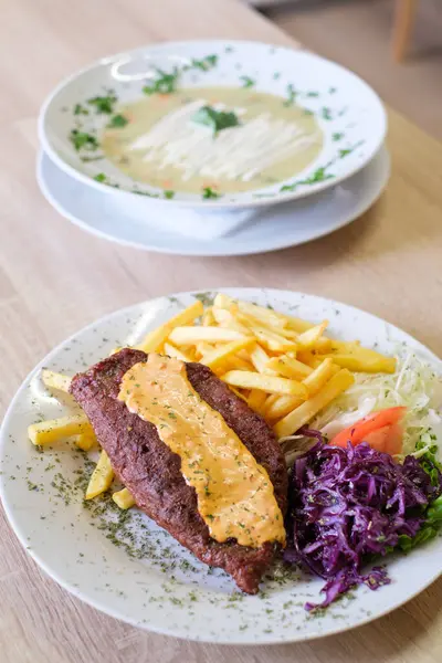 Patates kızartması, kırmızı lahana ve kremalı sosla servis edilen tuzlu köfte.