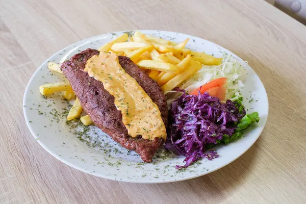 Patates kızartması ve yanında salata ile servis edilen kremalı soslu ızgara köfte.