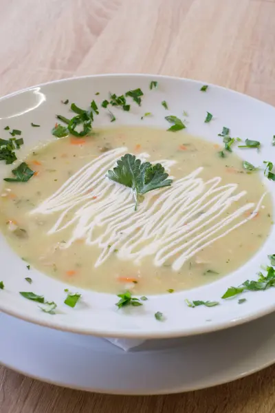 Taze bitkilerle süslenmiş kremalı çorba ve bir tutam sos.