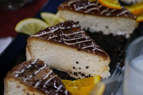 Çikolata yağmuru ve narenciye ile süslenmiş kremalı cheesecake dilimleri.