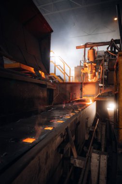 Erimiş metal, bir metal dökümhanesinde taşıyıcı bant boyunca akar.