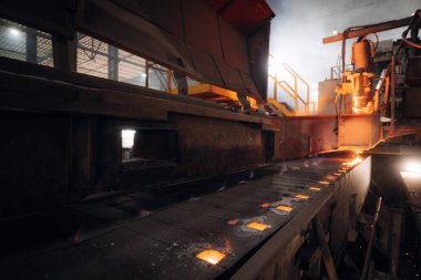 Erimiş metal endüstriyel ortamda bir taşıyıcı boyunca akar.