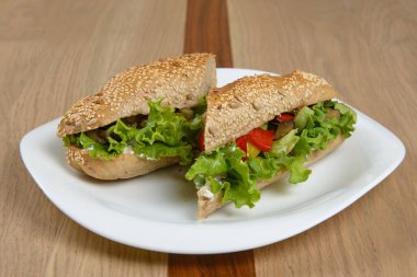 Taze marul biberleri ve diğer renkli sebzelerle dolu beyaz tabakta nefis bir sandviç.