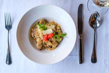 Parmesan ve vişneli domateslerle süslenmiş kremalı mantarlı risotto.