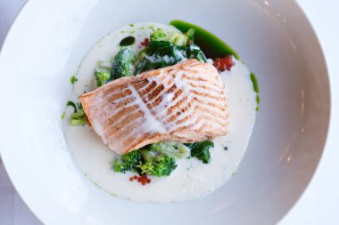 Kremalı soslu brokoli ve ıspanakla servis edilen tavada kurutulmuş somon filetosu.