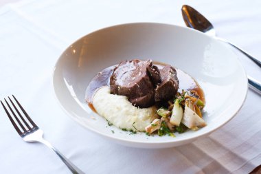 Yavaş pişmiş et, kremalı patates püresi ve kızarmış sebze içeren nefis bir yemek.