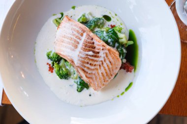 Sotelenmiş brokoli ve ıspanak soslu tavada kurutulmuş somon filetosu.