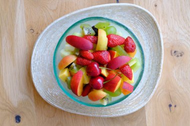 İçinde çilek, şeftali ve kiraz bulunan canlı bir meyve salatası.