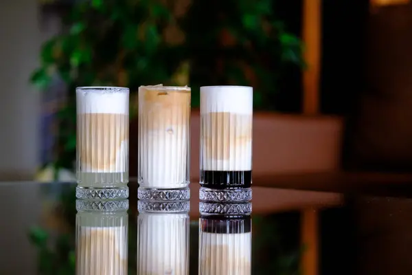 Zarif bardaklarda üç katmanlı buzlu kahve.