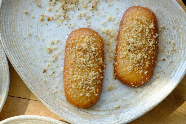 Kesilmiş fındıklı iki dikdörtgen hamur işi ve tabakta açık yeşil bir dinlenme.